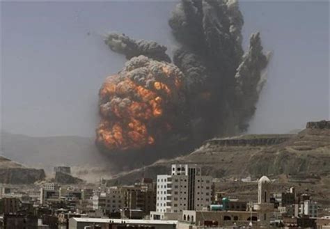 Bombardierung einer Stadt im Jemen. Im Vordergrund Hochhäuser im Hintergrund eine riesige bedrohliche schwarzgraue Explosionswolke über der Stadt und den Bergen. Krieg seit 2015 im Jemen.